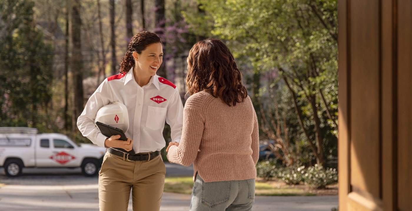 An Orkin Pro greeting a customer at her front door