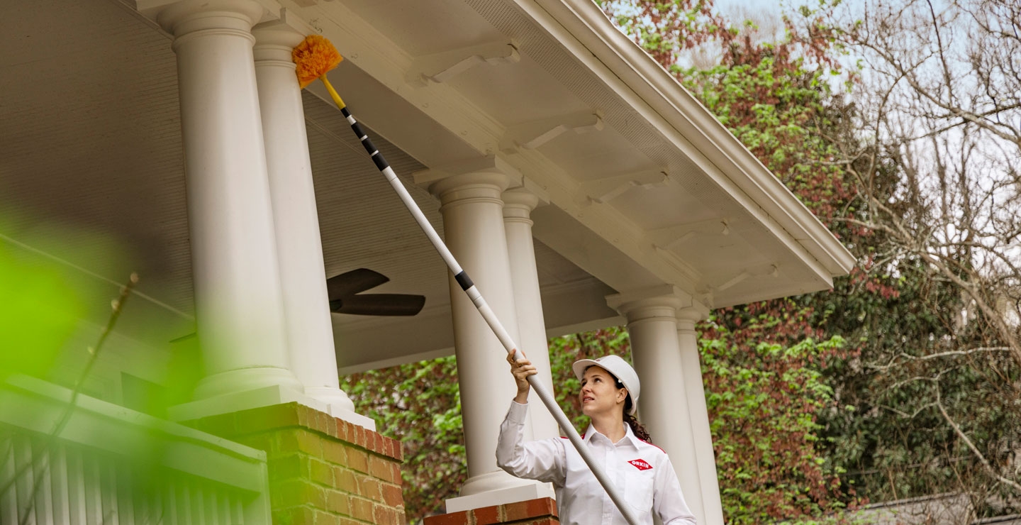 An Orkin Pro dusting the porch columns of a customer's home