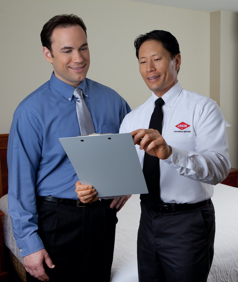 Orkin Pro explaining bed bug insights with customer in hotel room