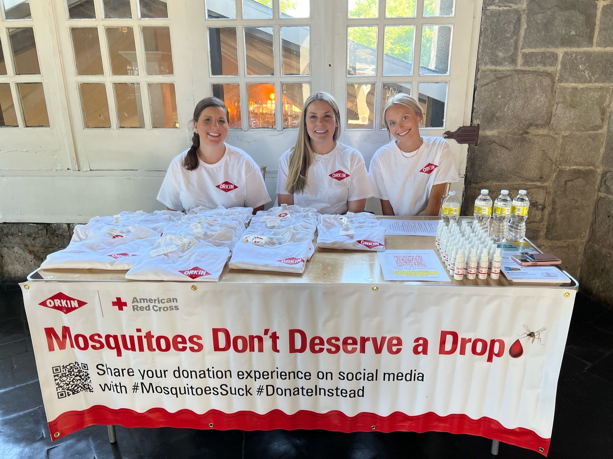 Orkin Atlanta 2022 Blood Drive. Mosquitoes Don't Deserve a Drop decorated table with three smiling Orkin Employees. 