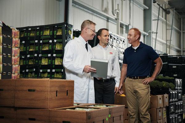Two Orkin Pros looking at a clipboard with a client in a warehouse-600x400
