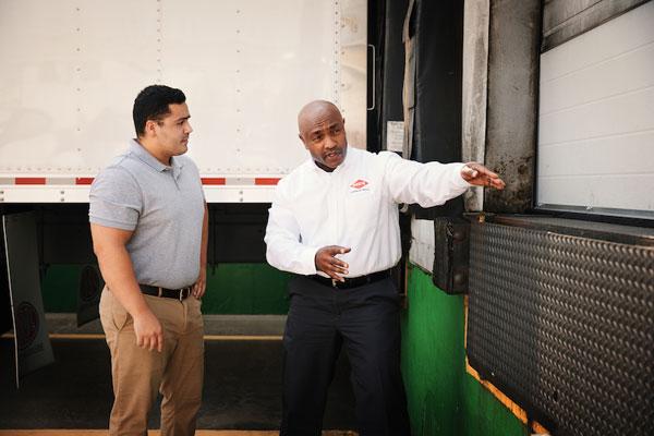 An Orkin Pro talking to a client in front of a loading dock-600x400