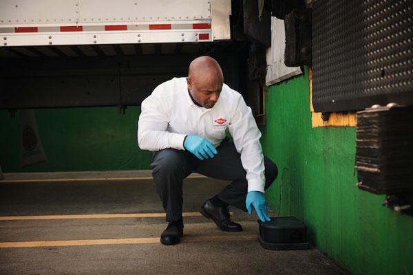 An Orkin Pro placing a rodent trap on a loading dock