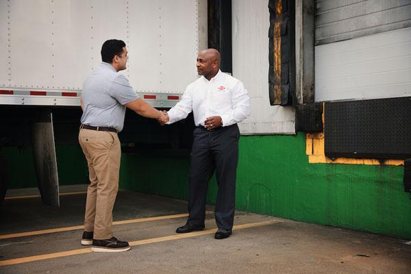 An Orkin Pro shaking hands with a client on a loading dock