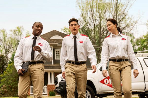 Three Orkin Pros leaving their Orkin truck and walking to a customer's home