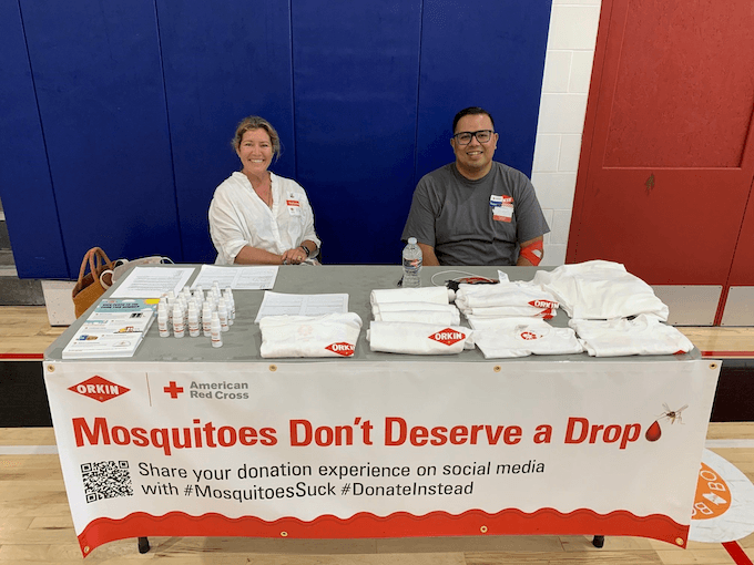 Orkin Los Angeles 2022 Blood Drive. Mosquitoes Don't Deserve a Drop decorated table with two smiling Orkin Employees. 