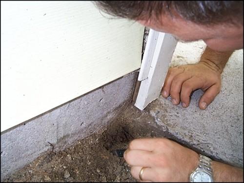 Termite Inspector Looking For Termites In Soil Next To Home
